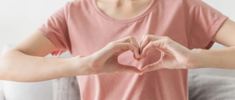 Woman making a heart shape with her hands, symbolizing heart health