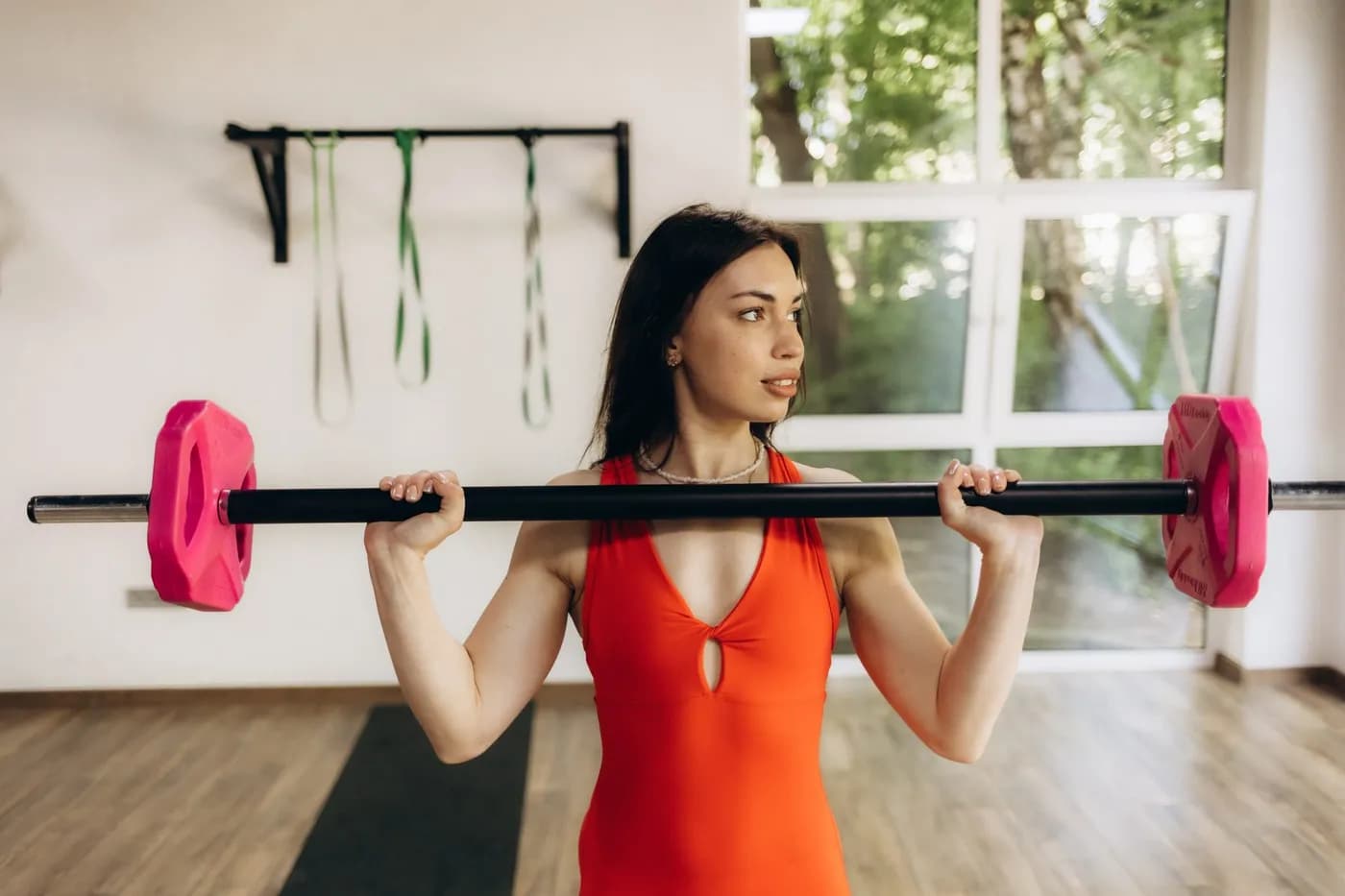 Woman lifting a barbell in a bright fitness studio