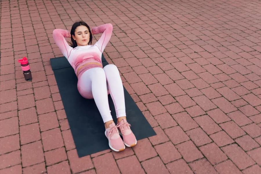 Woman performing sit-up exercise variation outdoors
