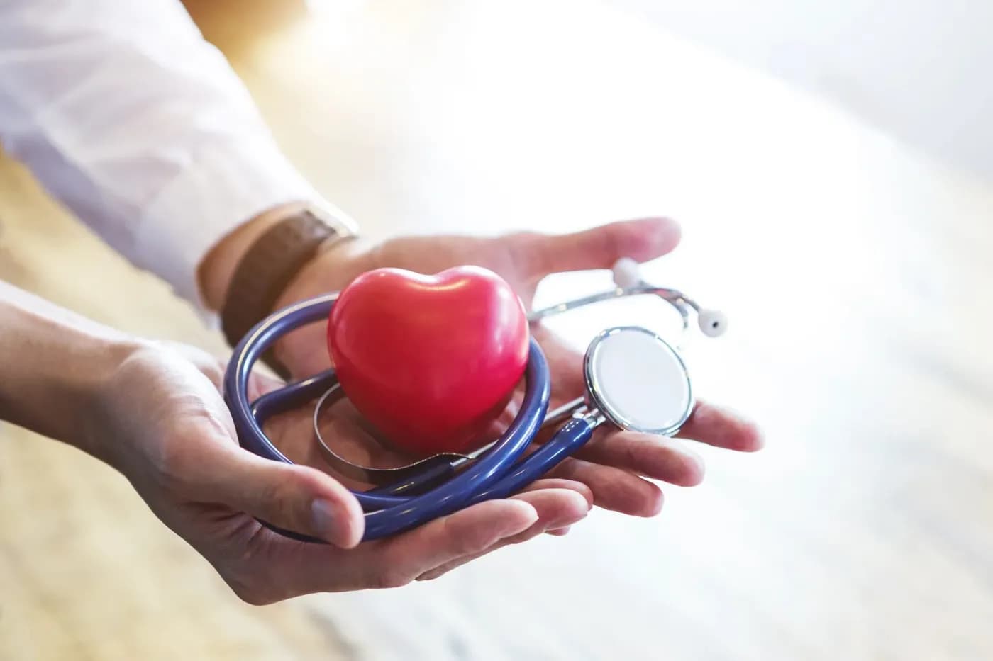 Hands holding a red heart and stethoscope